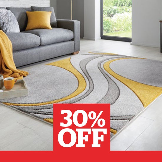 A large low-pile grey rug with a darker grey and yellow swirl design on a grey laminate floor